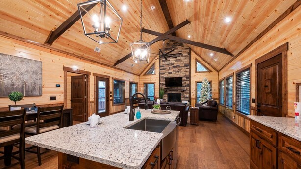 A spacious kitchen with granite countertops, a central island, and a stone fireplace. - High-End Romantic 1 Bedroom Cabin in highly sought after Timber Creek area (Broken Bow)