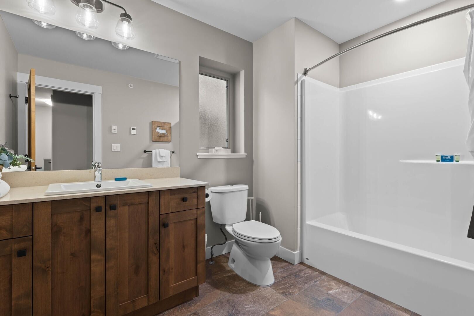 Une salle de bain moderne avec un meuble-lavabo en bois, des toilettes et une douche à l’italienne.