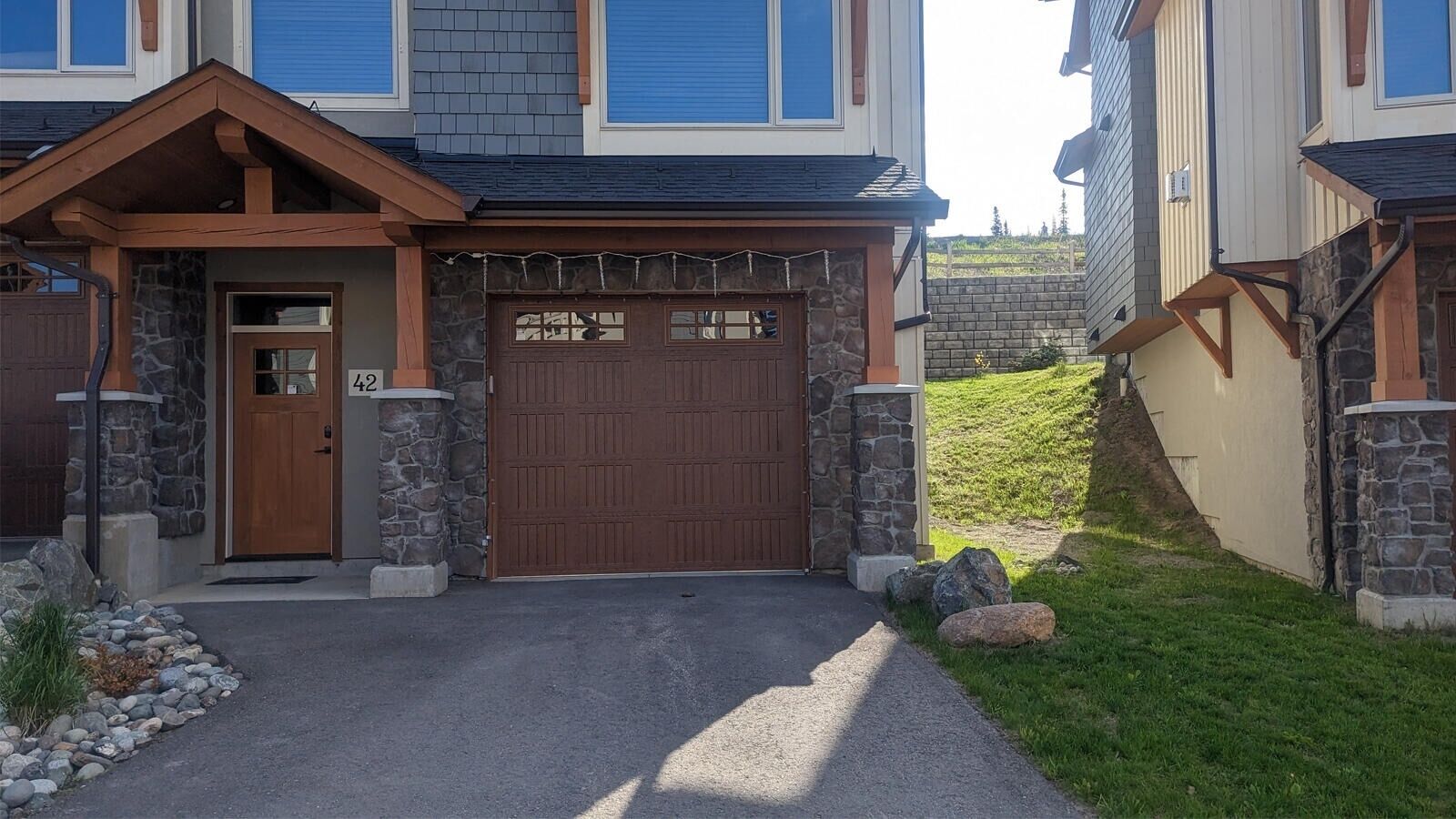 A two-story house with a stone facade, a wooden front door, and a garage.