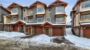 A multi-story residential building with a symmetrical facade, large windows, and a stone foundation.