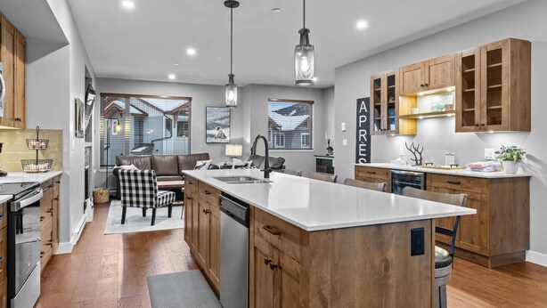 A modern kitchen with wooden cabinets, a central island, and pendant lighting.