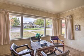 Enjoy a classic room with a large window offering a view of the outside, a wooden table, two chairs, and a vase of flowers.
