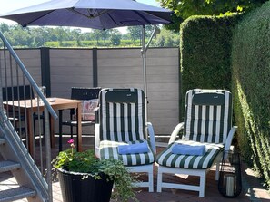 An outdoor seating area with two striped chairs, a table, and a large umbrella.