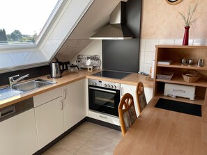 A modern kitchen with a built-in oven, a stove, a sink, and a window above the sink. - Am Nordwald ***** Vacation Apartment, Saterland - Am Nordwald ***** Vacation Apartment, (Saterland)