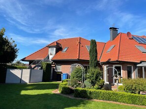 A house with a red-tiled roof, a chimney, and a well-maintained garden.