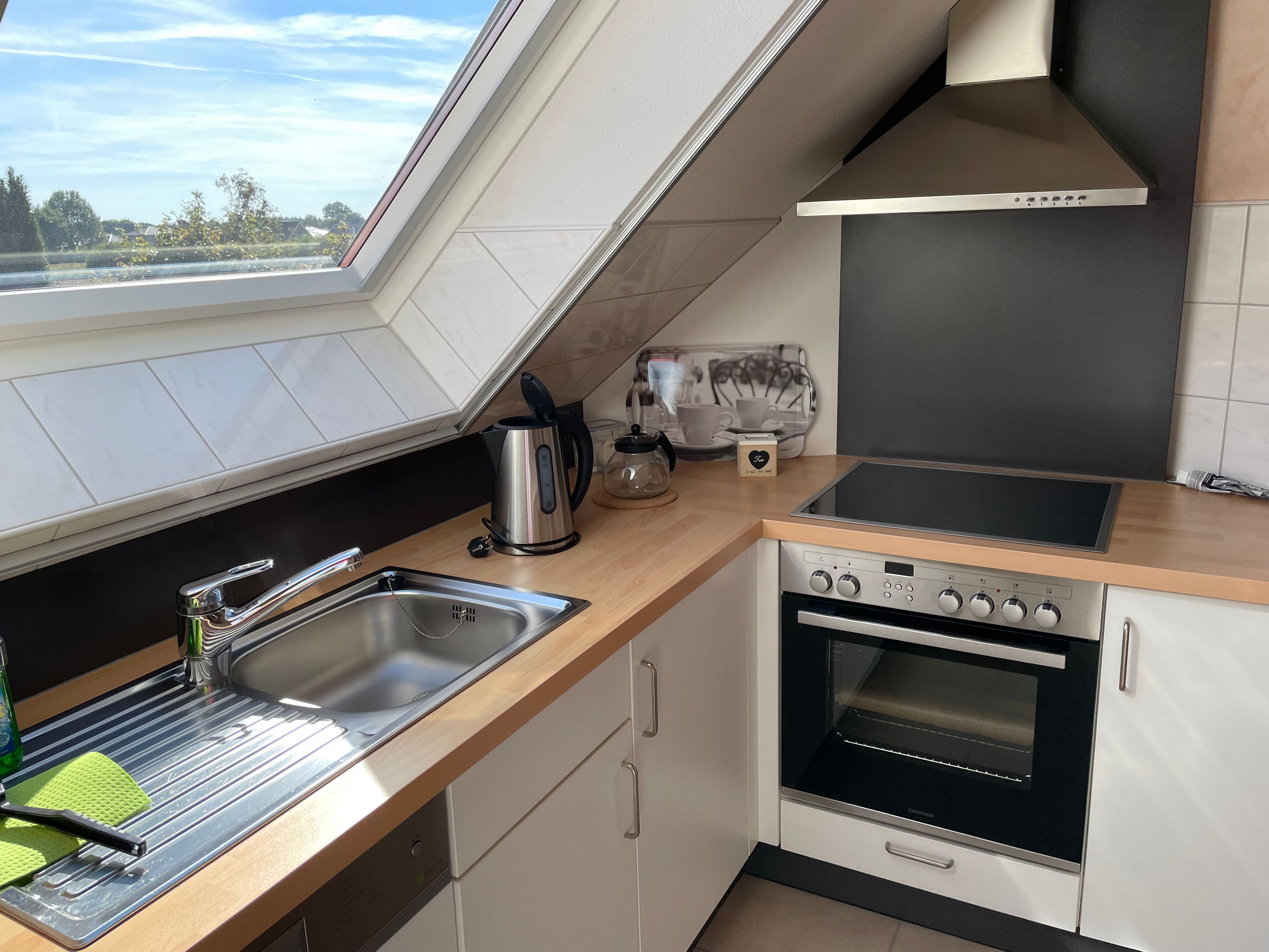 A modern kitchen with a skylight, stainless steel appliances, and a view of the outdoors.