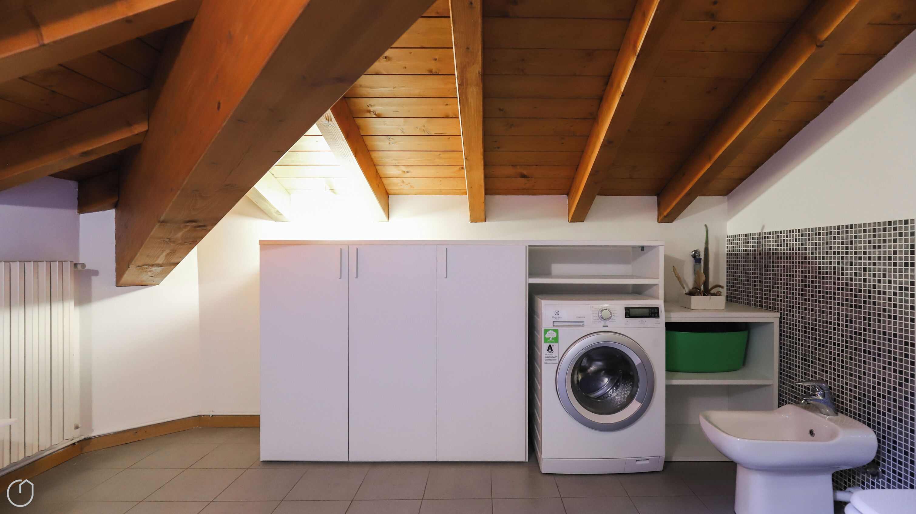 A laundry room with a washing machine, a cabinet, and a bidet.