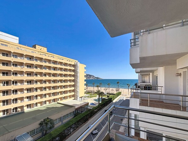 A hotel with multiple balconies overlooking a beach and the sea.