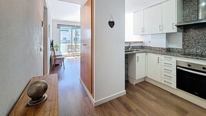 A modern kitchen with white cabinets, a granite countertop, and a built-in oven. - R. MARINE II 434 Roses / Roses - INTERimmo (Rosas / Roses)