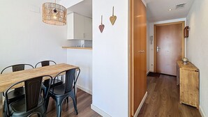 A modern kitchen with white cabinets, a wooden dining table, and black chairs. - R. MARINE II 434 Roses / Roses - INTERimmo (Rosas / Roses)