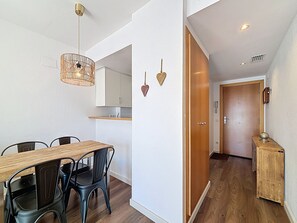 A modern kitchen with white cabinets, a wooden dining table, and black chairs.