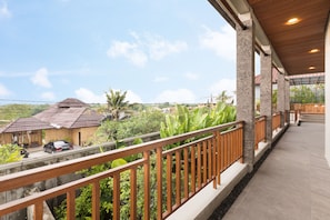 A balcony with a wooden railing overlooking a residential area with houses and greenery. -  Villa Daun 2 Canggu by Premier Hospitality Asia (Canggu)