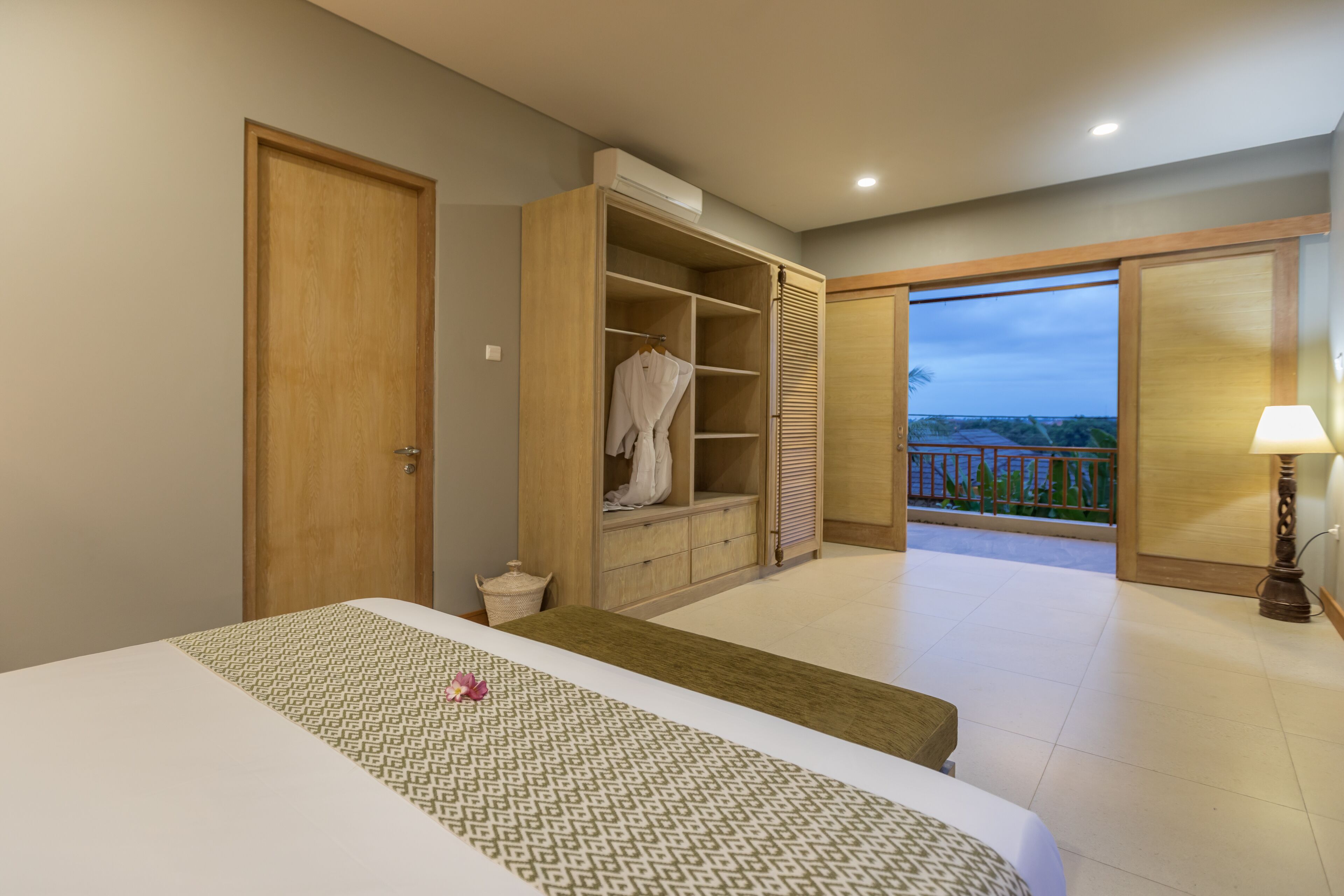 A hotel room with a bed, a walk-in closet, and a balcony with a view.