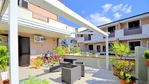 An outdoor patio area with wicker furniture, potted plants, and a bicycle. - Casa Pesca C: A modern and graceful apartment situated at a few steps from a sandy beach, with Free WI-FI. (Agropoli)