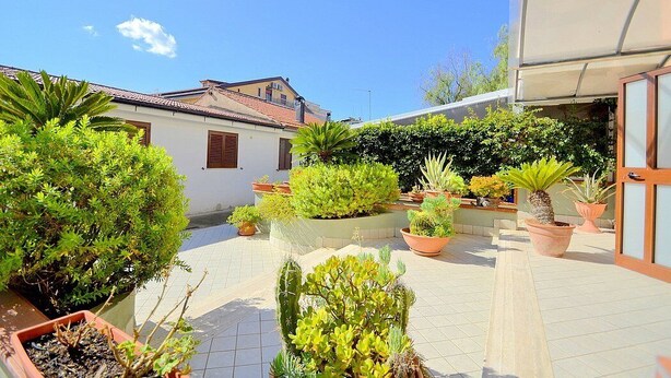 A courtyard with potted plants, a white building, and a tiled floor. - Casa Pesca C: A modern and graceful apartment situated at a few steps from a sandy beach, with Free WI-FI. (Agropoli)
