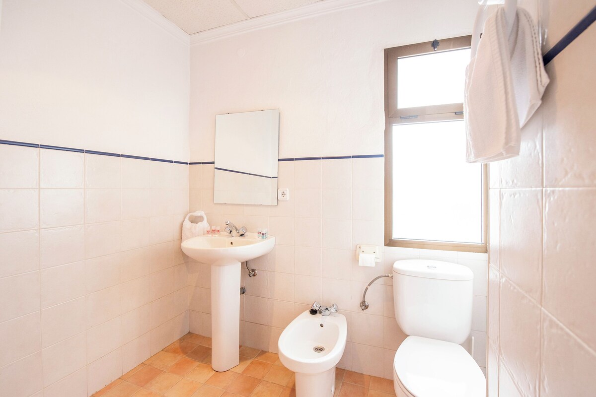 Un baño pequeño y limpio con lavamanos pedestal, un bidé y un inodoro.