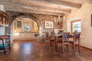 A rustic kitchen with stone walls, wooden cabinets, and a dining area with a table and chairs. - Rustic Villa Lavanda - Pool & Garden (Koper)
