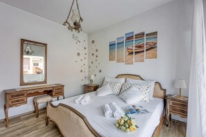 Siististi järjestetty makuuhuone, jossa on sänky, yöpöydät, lipasto, peili ja seinätaideteoksia.