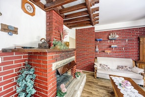 Una sala de estar con chimenea de ladrillo, un sofá blanco y una mesa de centro de madera.