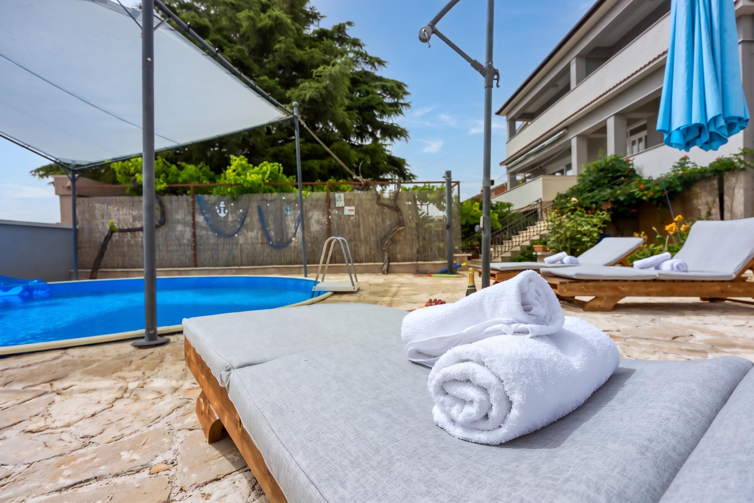 A poolside area with a lounge chair, a towel, and a wooden deck.