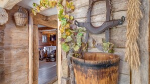 Een rustiek houten interieur met een houten vat, een metalen haak en hangende wijnranken.