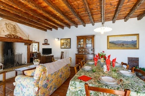 A dining area with a wooden ceiling, a fireplace, a sofa, and a table set for a meal. - Villa Formaga Stunning View&garden and (Gargnano)