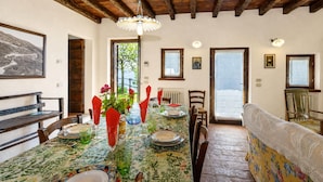 Comedor con una mesa dispuesta para cuatro, vigas de madera en el techo y vistas al exterior a través de una ventana.
