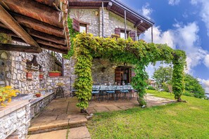 A stone building with a wooden balcony and a table set for dining.