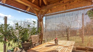 A wooden deck with a table and chairs, surrounded by potted plants and a bamboo screen. - Vineyard Cottage Bahor (Crnomelj)