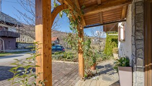 A covered outdoor area with a wooden pergola, potted plants, and a stone wall. - Vineyard Cottage Bahor (Crnomelj)