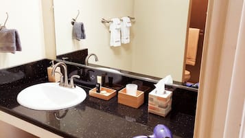 Un baño con lavamanos, espejo y toallero.