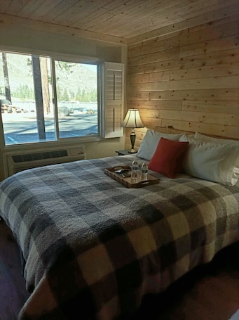 A room with a bed, a window, a lamp, and a tray with bottles.