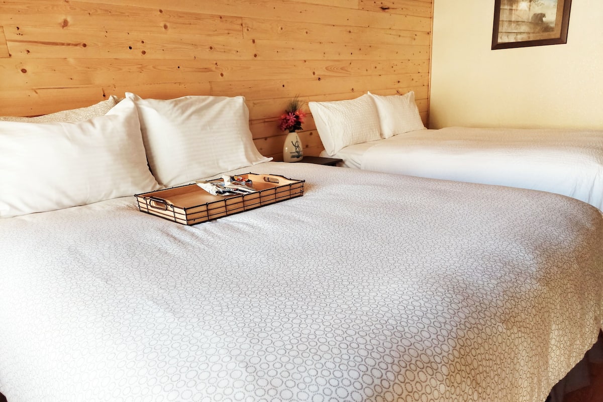 A double bed with a wooden headboard, white bedding, and a tray with items on it.