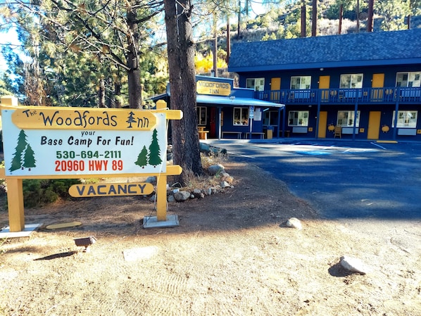 A sign for The Woodfords Inn, a base camp for fun, with contact details and a vacancy notice.