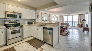Una cocina moderna con electrodomésticos de acero inoxidable, armarios blancos y una isla central con lavavajillas.