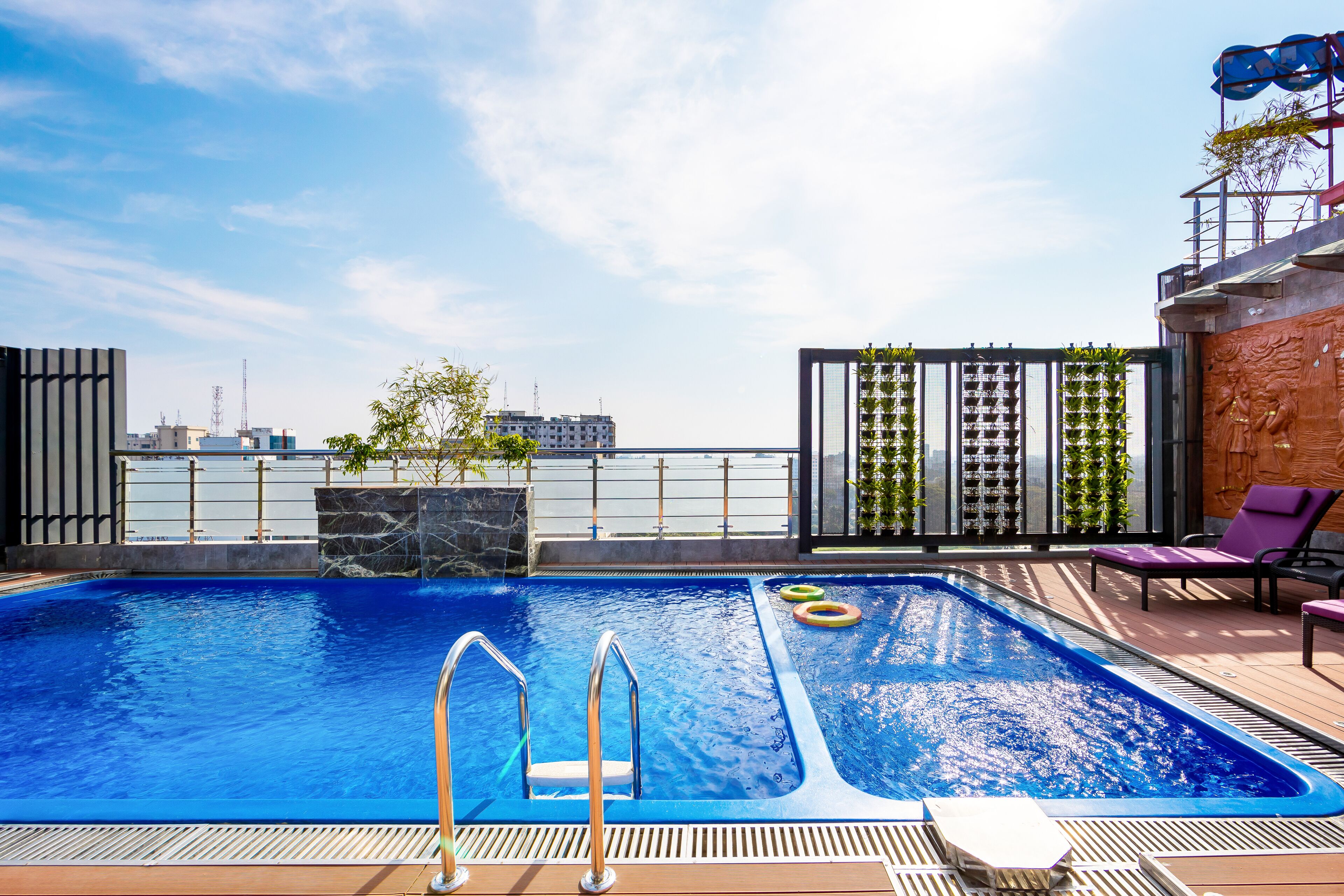 A rooftop pool with a clear view of the city skyline, a seating area with lounge chairs, and a modern architectural design.