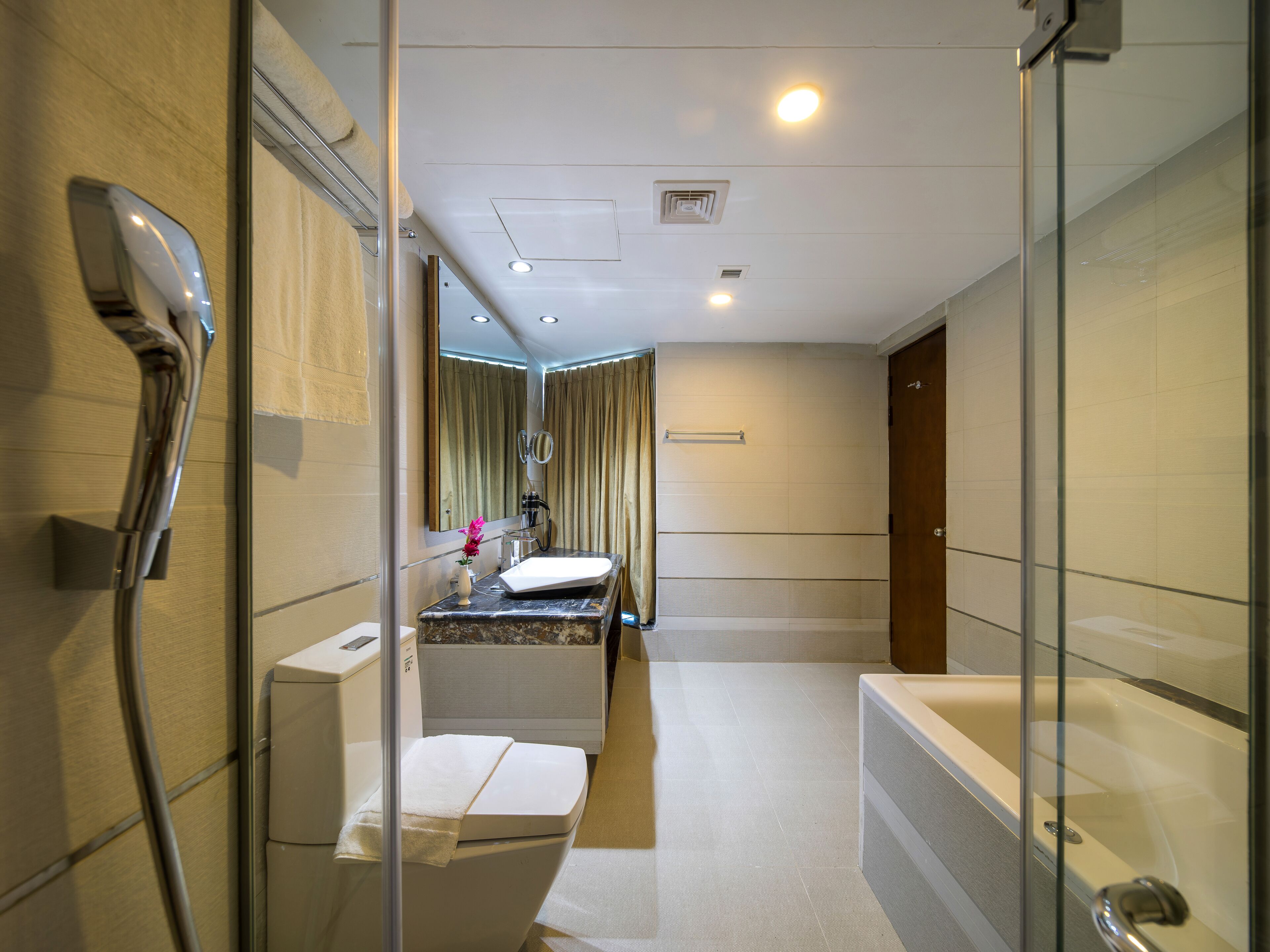 A modern bathroom with a glass shower enclosure, a bathtub, and a vanity with a mirror.