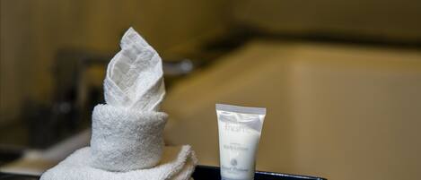 A white towel and a tube of fresh body lotion on a black tray.