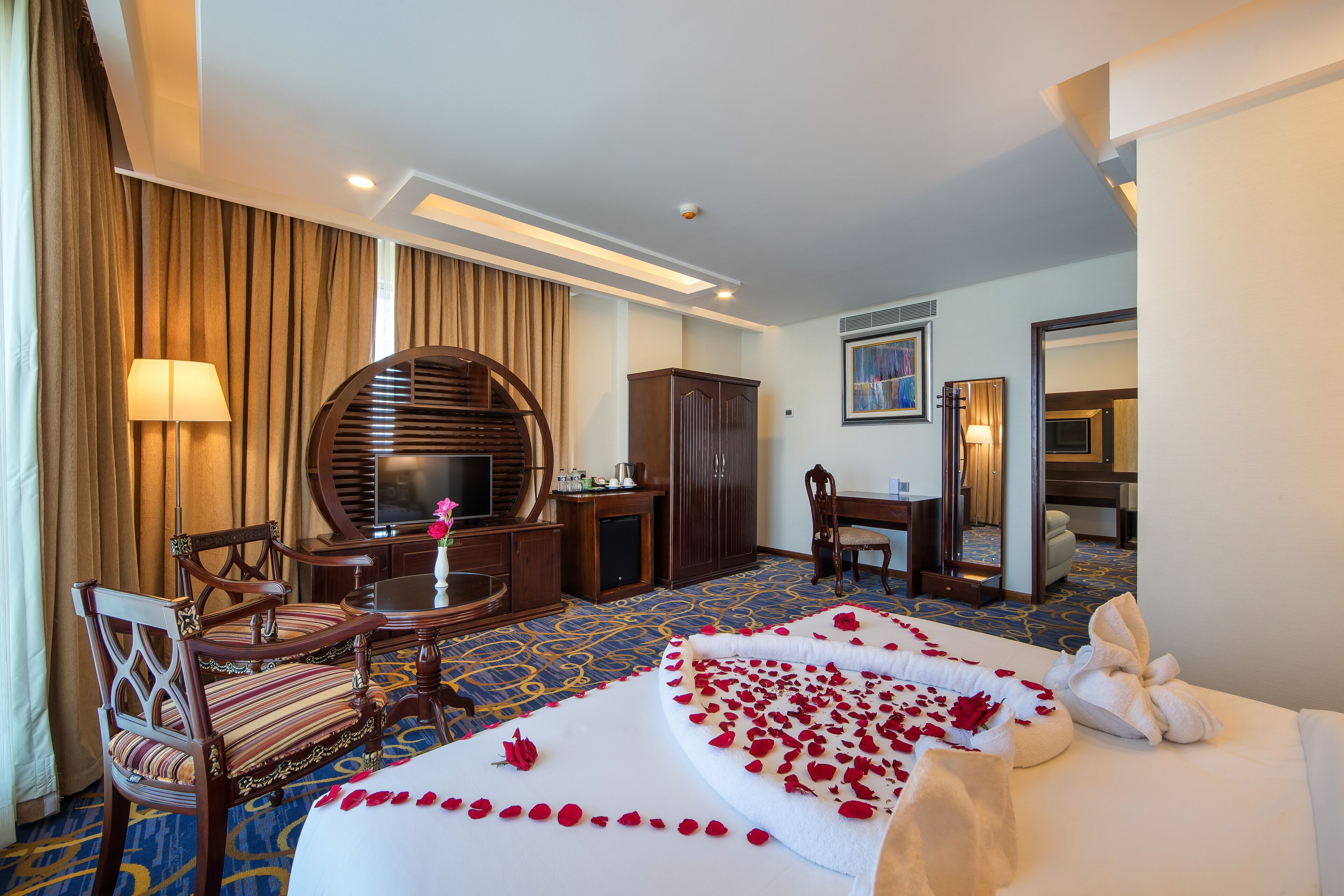 A hotel room with a bed, a desk, a chair, a TV, and a wardrobe.
