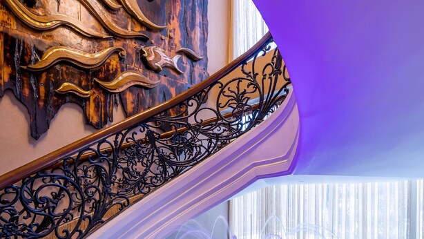 Un espace piscine intérieur luxueux, agrémenté d’un escalier en colimaçon et de décorations murales raffinées.
