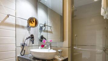 Un baño moderno con un espejo grande, un lavamanos con encimera de mármol y una cabina de ducha de vidrio.