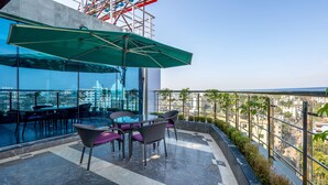 Une terrasse avec une table et des chaises, un parasol vert et une vue sur le paysage urbain.