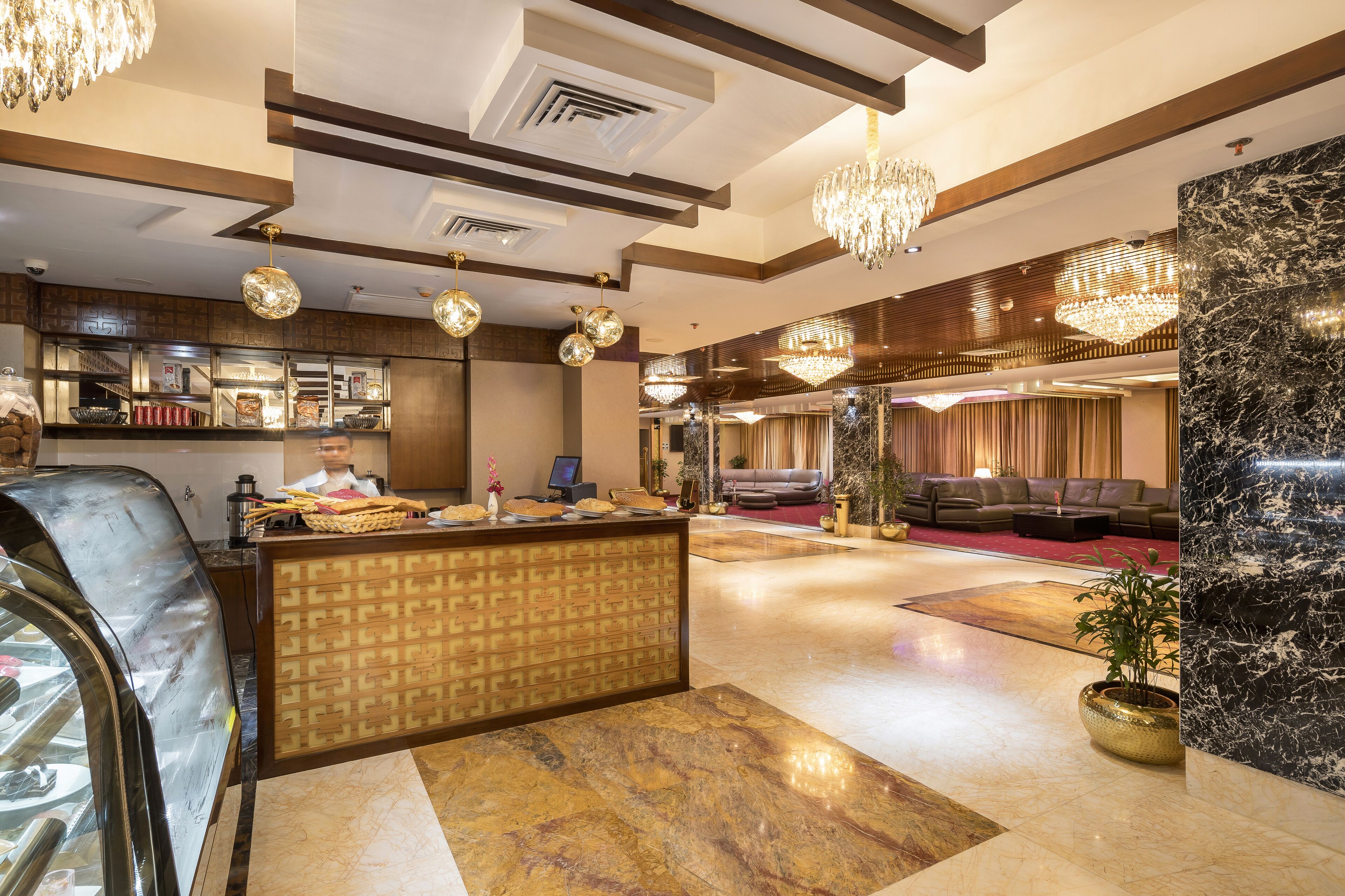 A hotel lobby with a reception desk, seating area, and a marble floor.