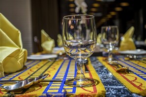 Een eettafel met een tafelkleed met patroon, een wijnglas en bestek.