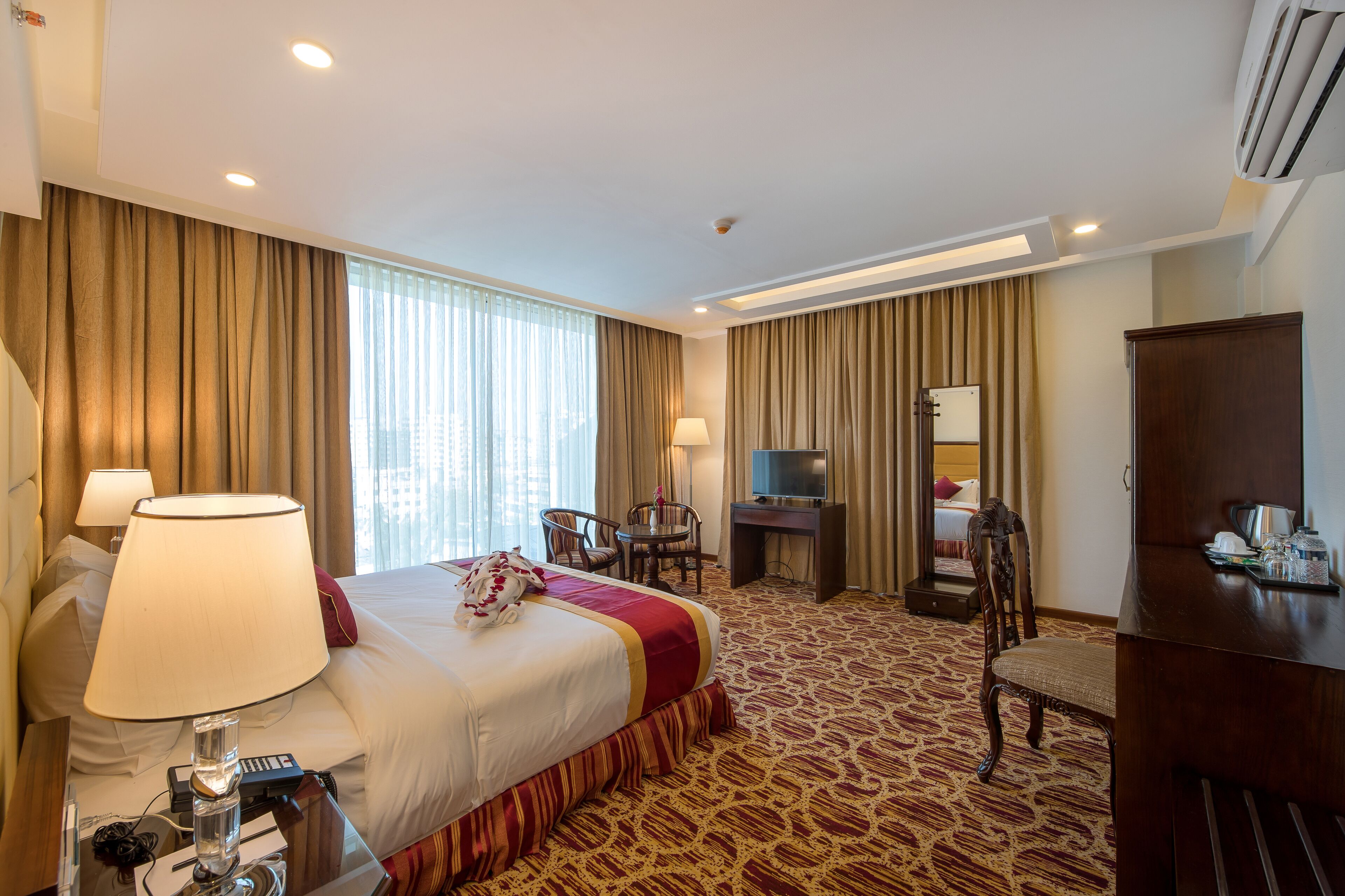 Une chambre d’hôtel avec un grand lit, un bureau, une chaise, une télévision et un minibar.