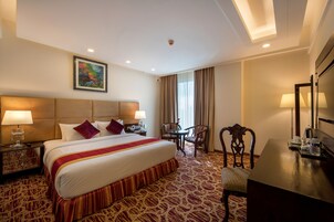 Una habitación de hotel con una cama grande, un escritorio, una silla, una mesa y un televisor.