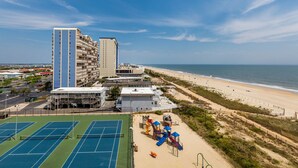 A coastal hotel with multiple high-rise buildings, a beach, and a tennis court. - Sea Watch 702 by Seaside Vacations & Sales (Ocean City)