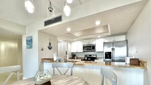 Una cocina moderna con gabinetes blancos, electrodomésticos de acero inoxidable y encimera de granito.