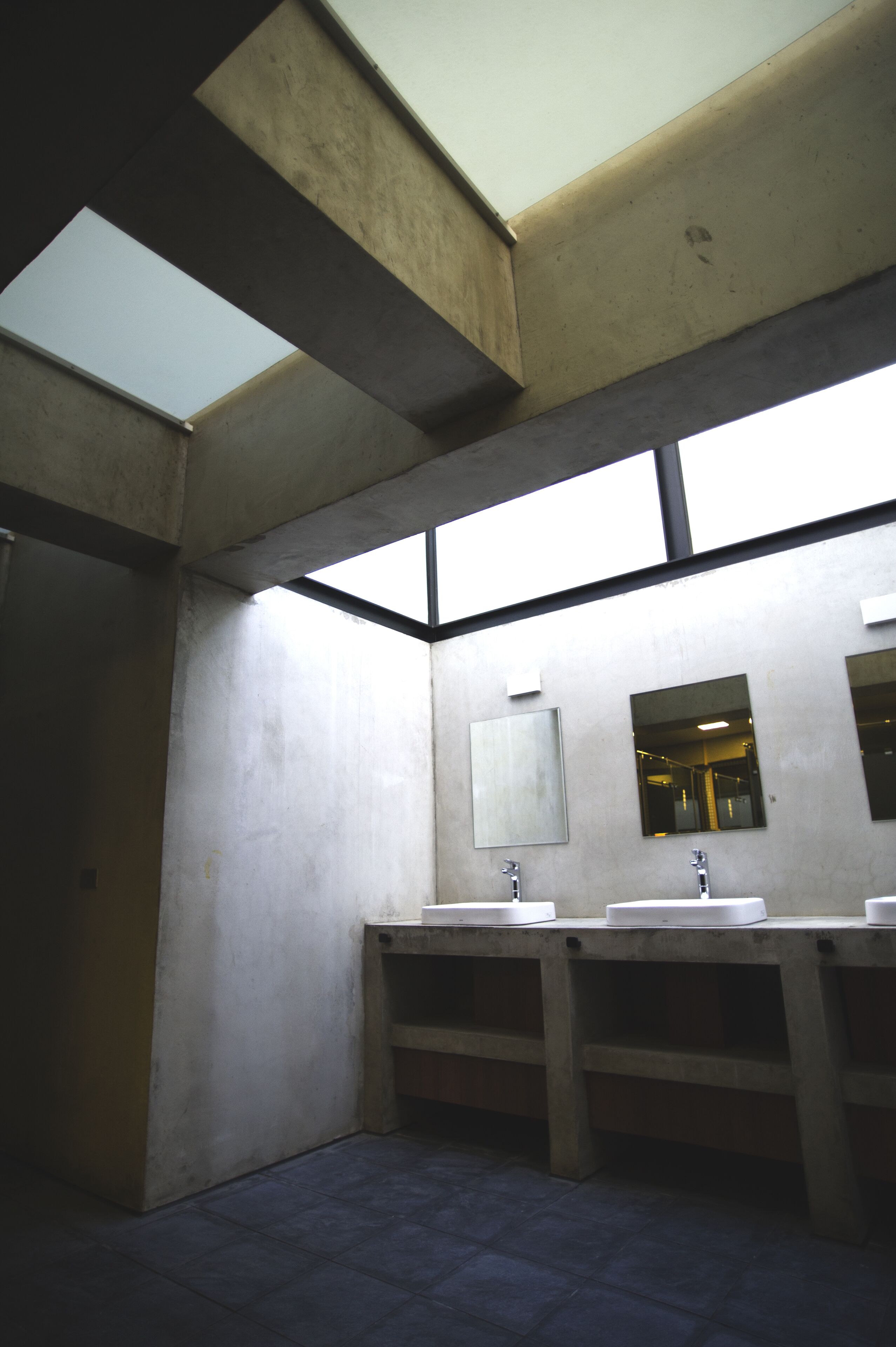 A restroom with two sinks, a mirror, and a skylight.