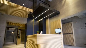 A modern reception area with a central desk, a digital screen, and a potted plant. - FFF Hotel (Hengchun)